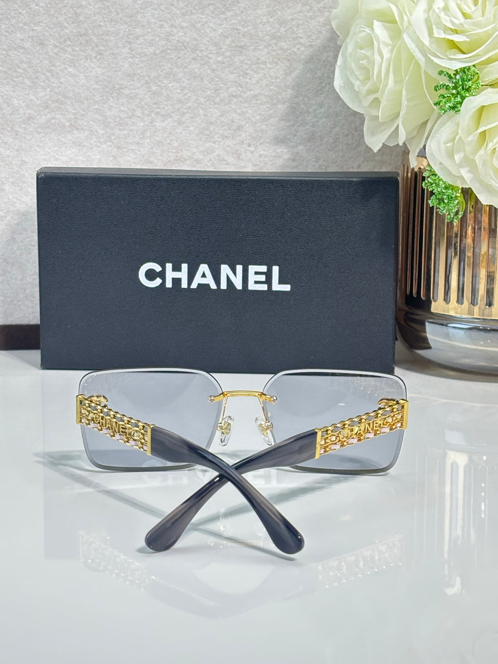 Chanel sunglasses with clear lenses and gold chain temple accents, rectangular frames