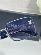 Chanel sunglasses close-up: blue lens with silver logo on chain temple