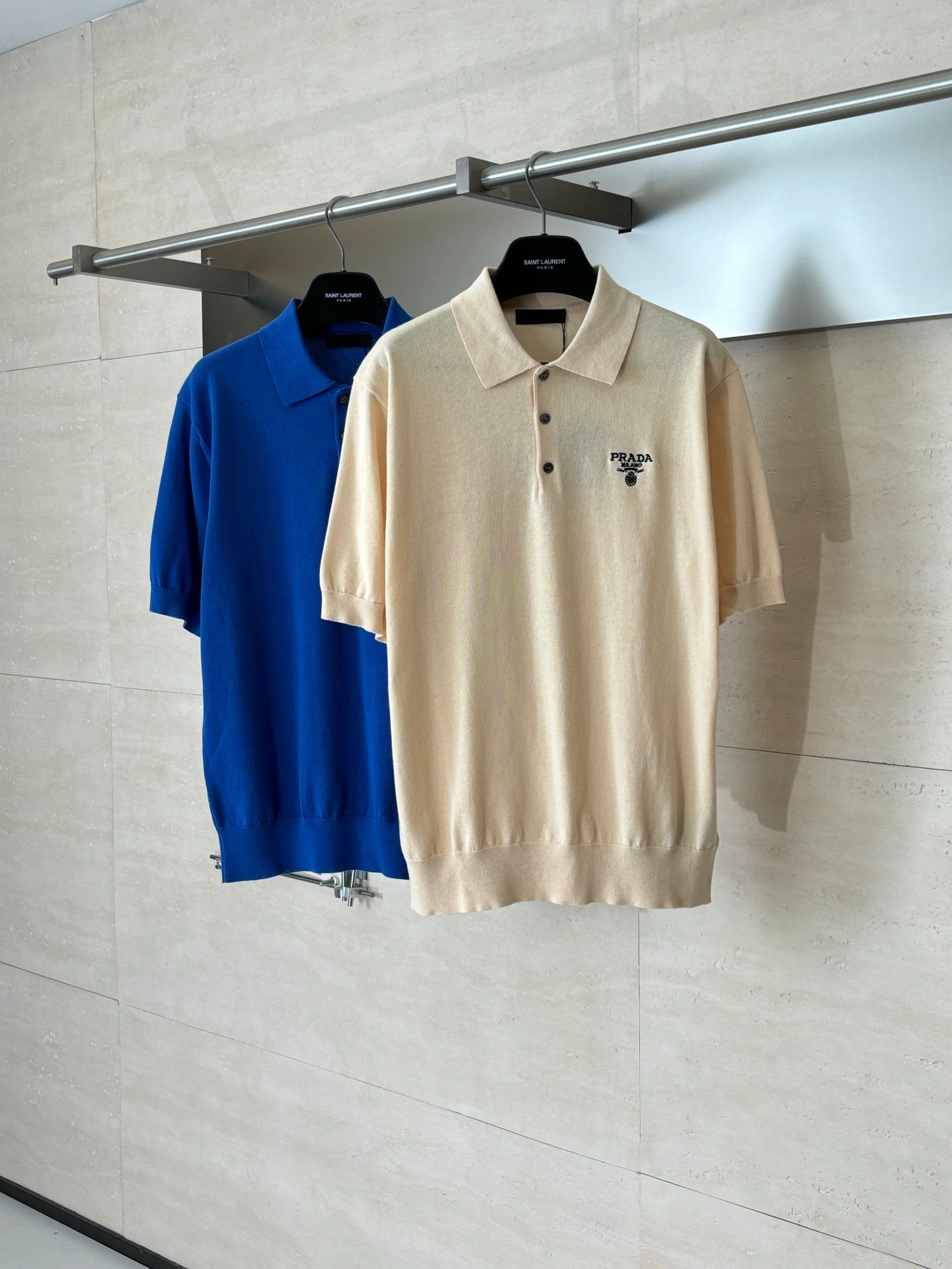 Two short-sleeve polo shirts on hangers: beige and blue