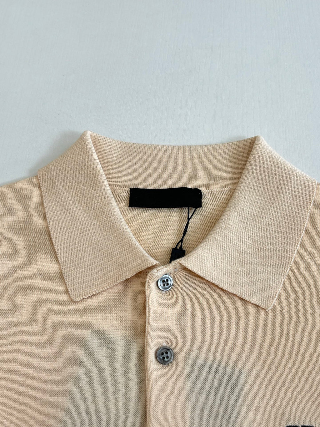 Beige polo shirt collar with two buttons and black interior neckline tag