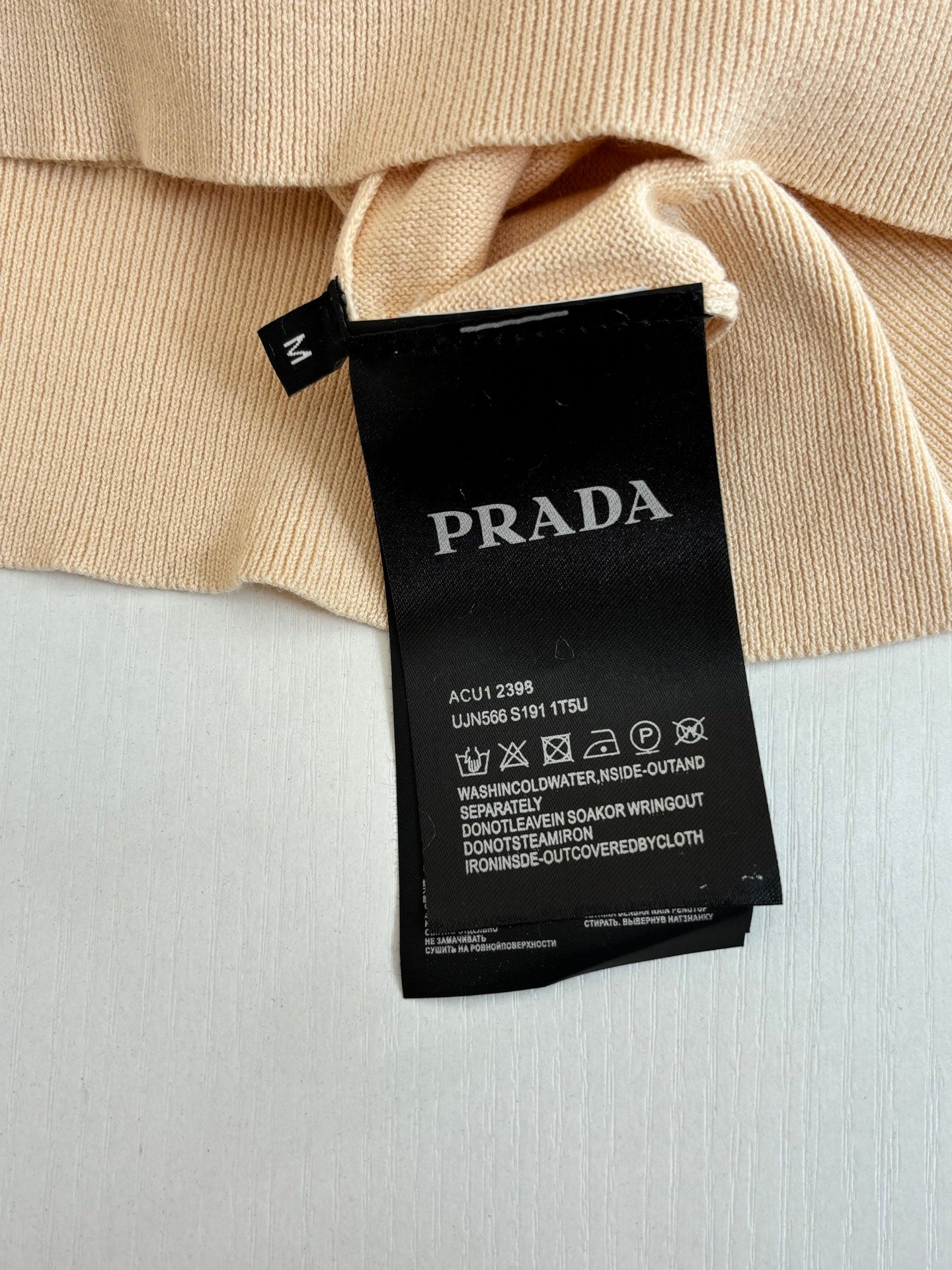 Beige polo shirt care label and size tag showing Prada branding