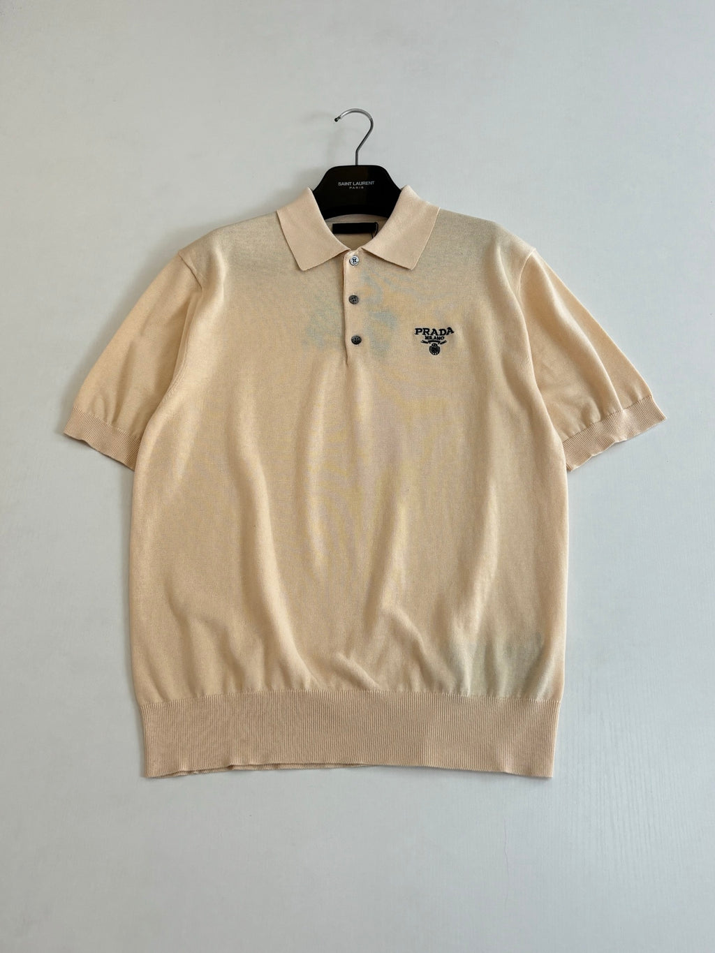 Beige short-sleeve polo shirt front view with buttoned collar and chest logo