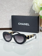 Black round sunglasses with gold-tone chain arms and tinted lenses