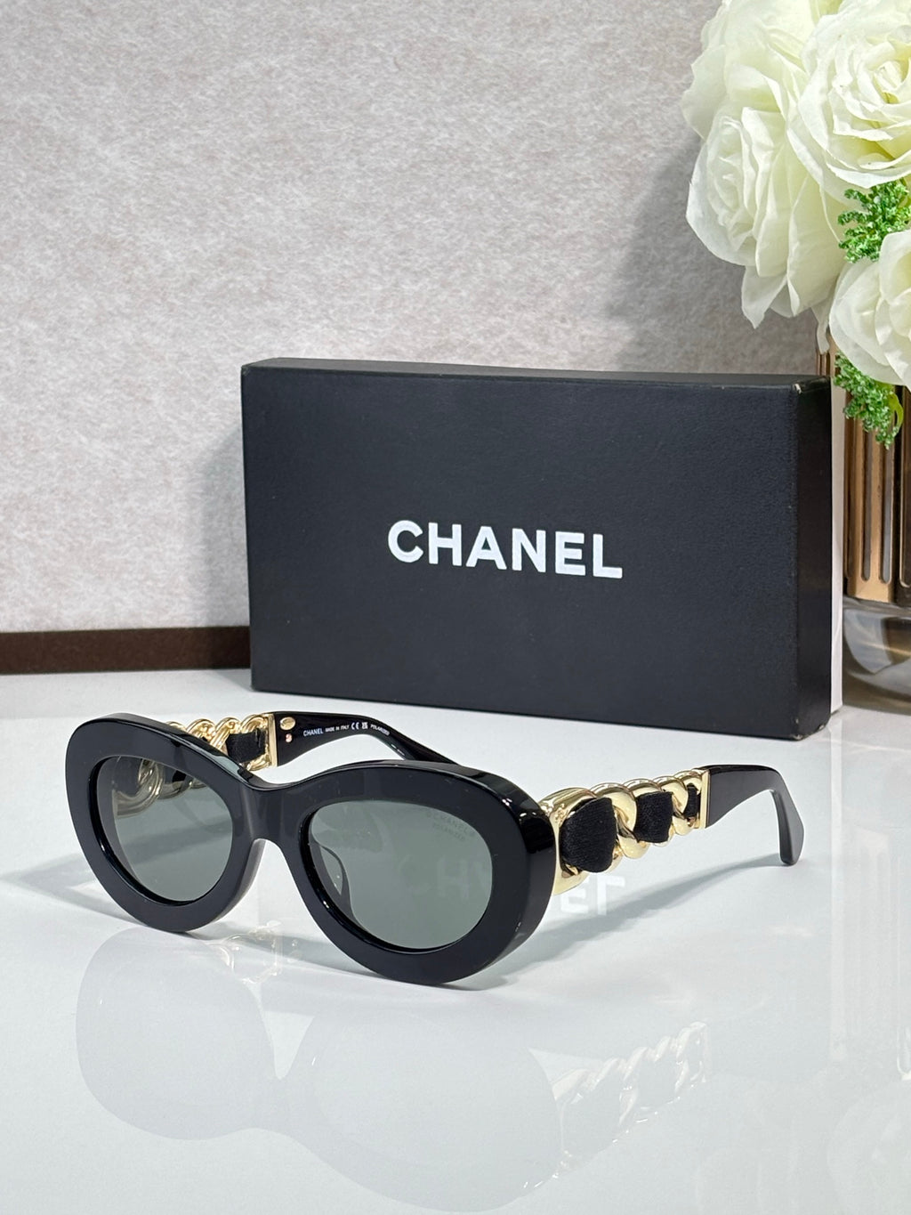 Black round sunglasses with gold-tone chain links and tinted lenses