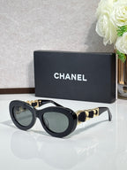 Black round sunglasses with gold-tone chain links and tinted lenses