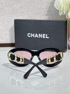 Black round sunglasses with gold-tone chain strap detail and tinted lenses