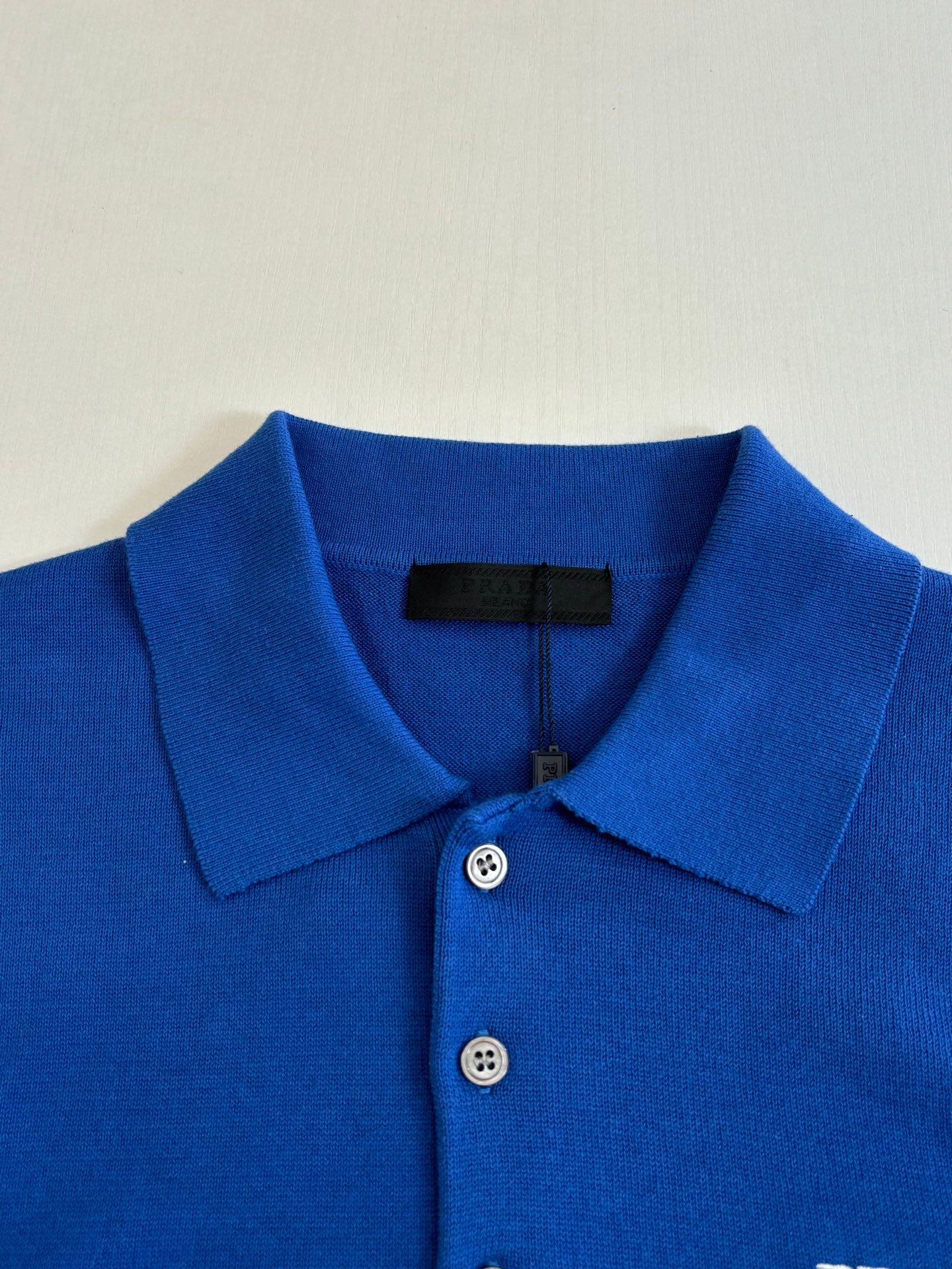 Blue polo shirt collar and button placket with Prada fabric tag