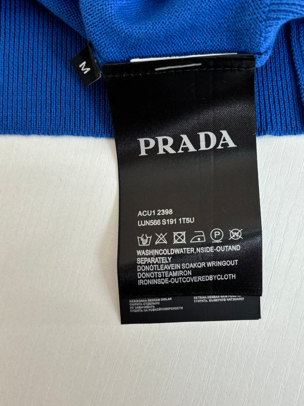 Blue knit polo size tag and black Prada label