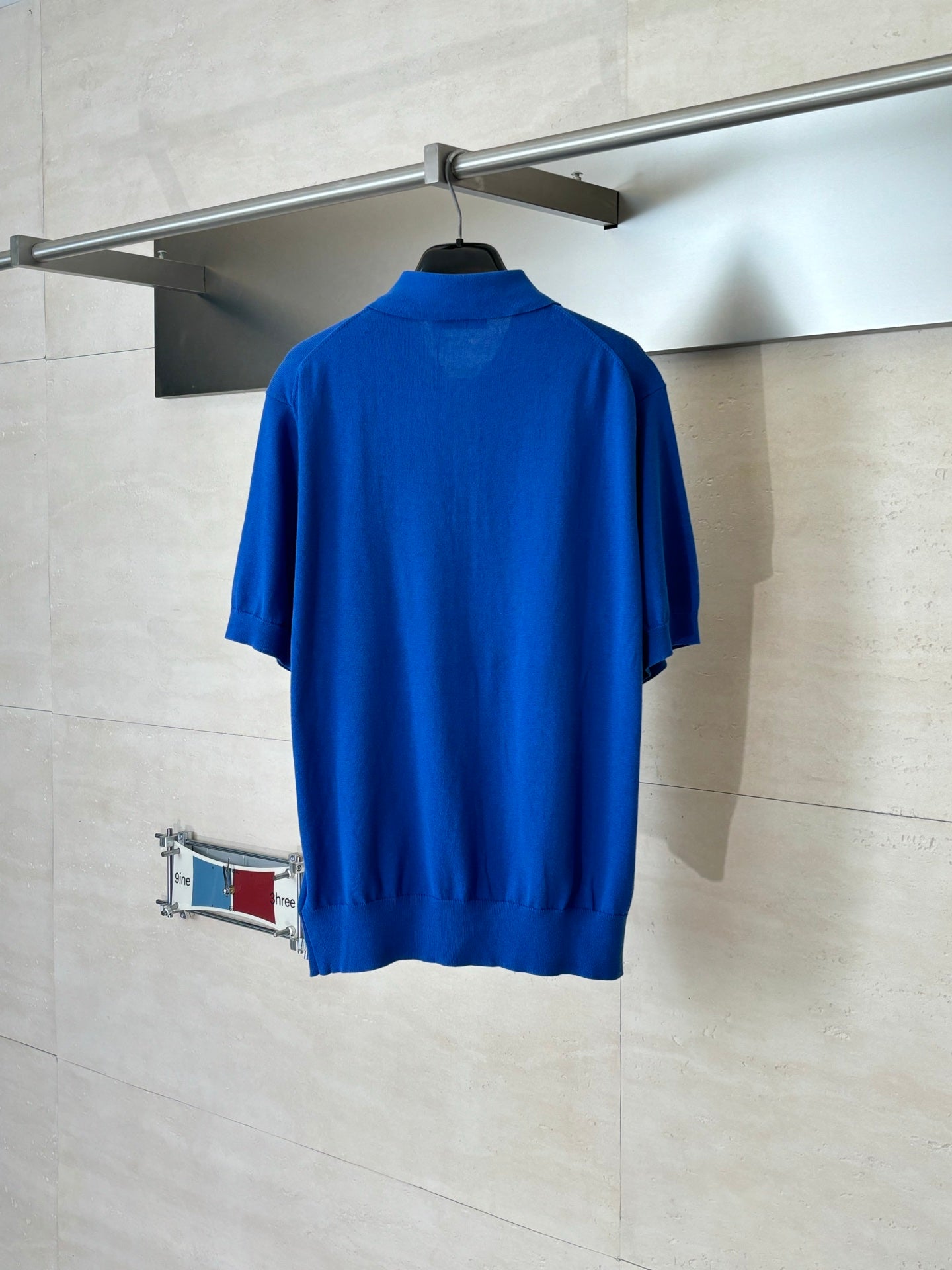 Blue short-sleeve polo shirt, back view on a hanger