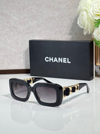Black square sunglasses with gold chain detail on the temples and tinted lenses