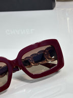 Maroon sunglasses with gold-link chain detail and tinted lens