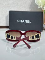 Burgundy sunglasses with gold chain detail on the sides and tinted lenses