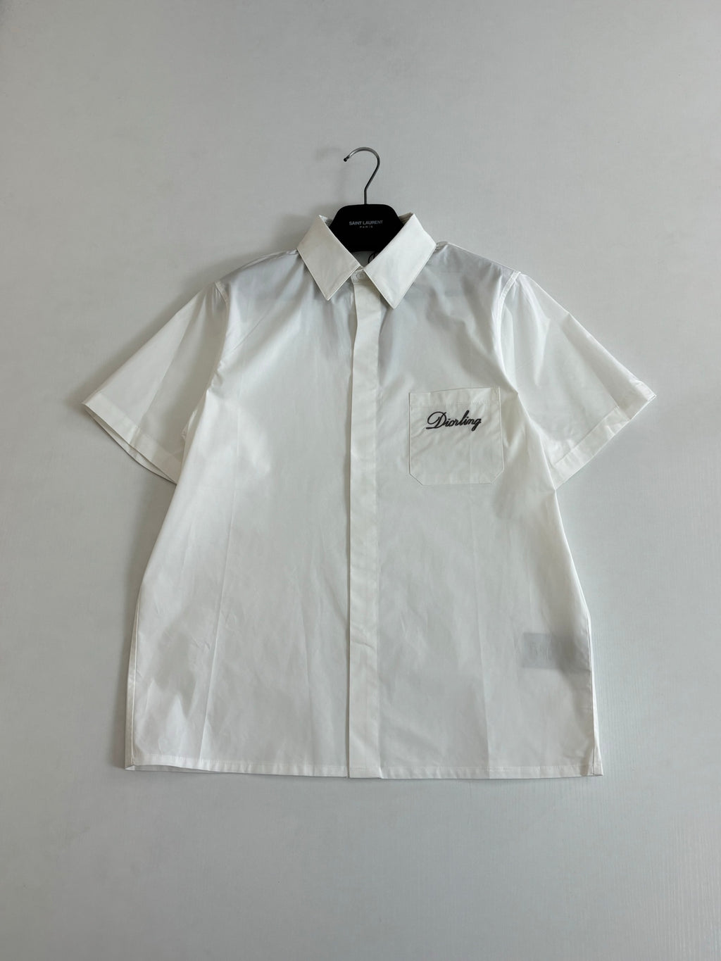 White short-sleeve button-up shirt with pointed collar and chest logo