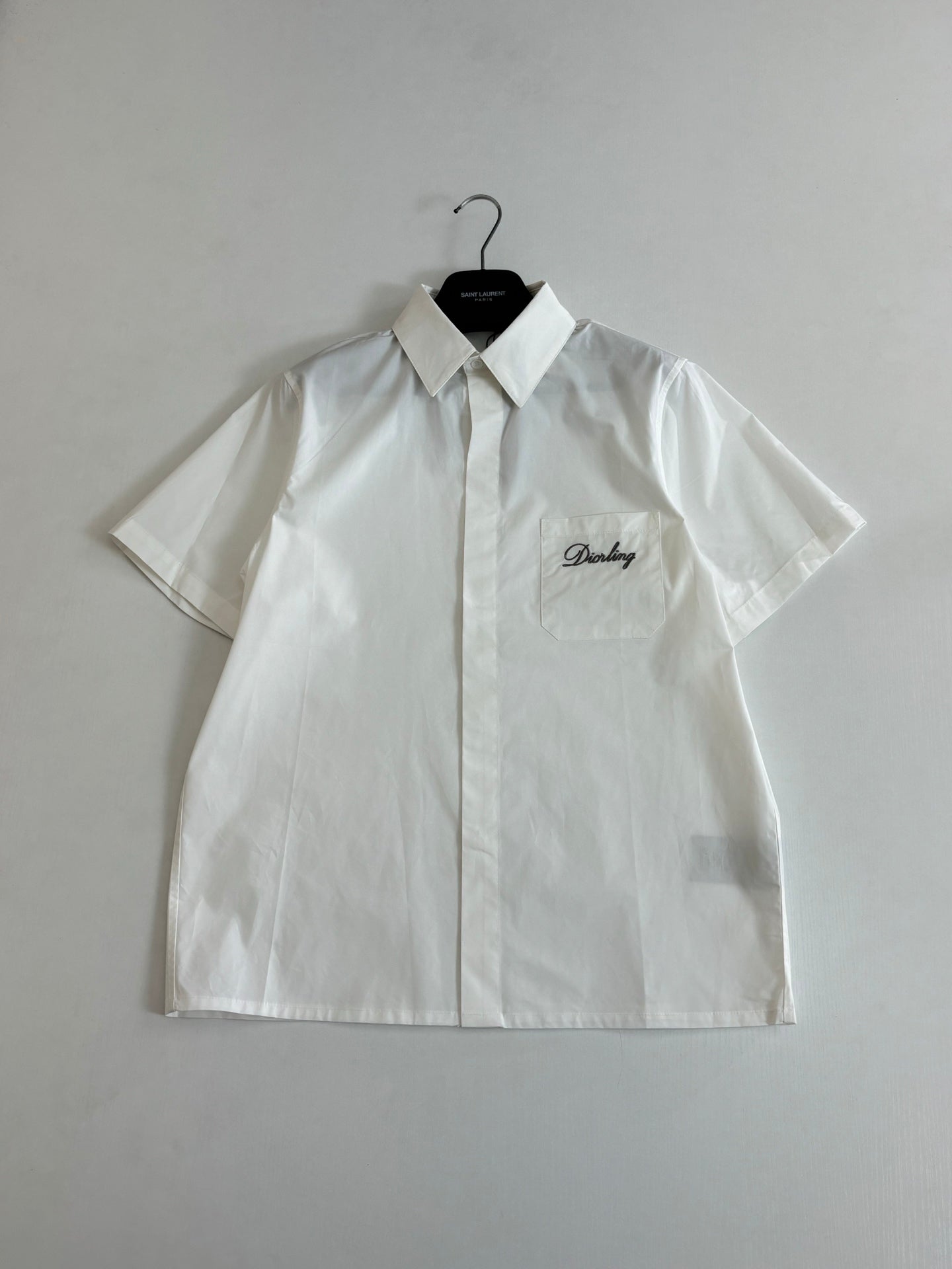 White short-sleeve button-up shirt with pointed collar and chest logo