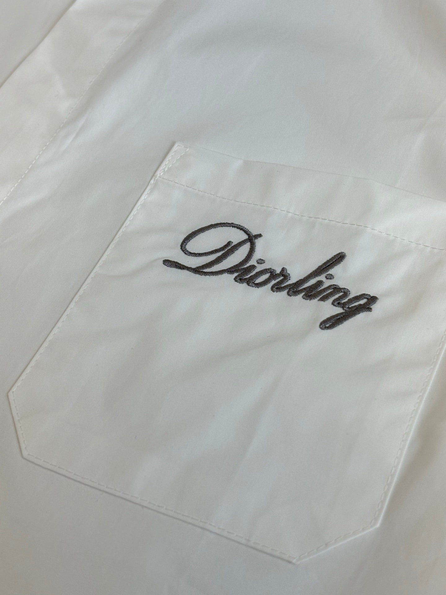 White shirt chest pocket with embroidered script logo
