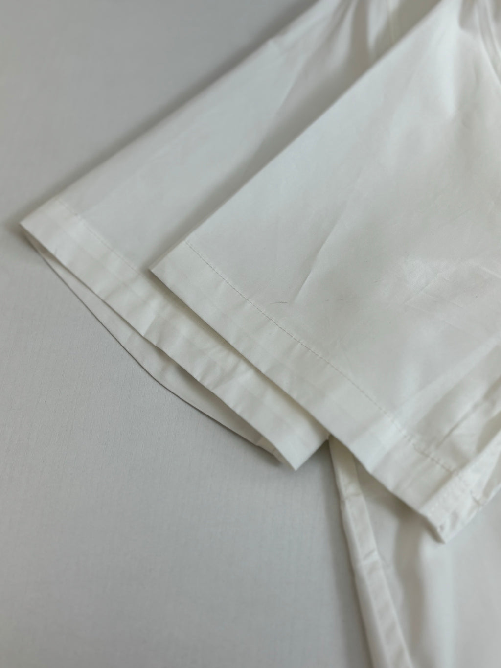 White shorts laid flat with stitched hem detail