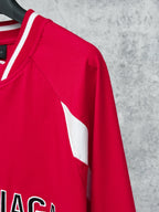 Red long-sleeve jersey side panel close-up with white stripe and stitching