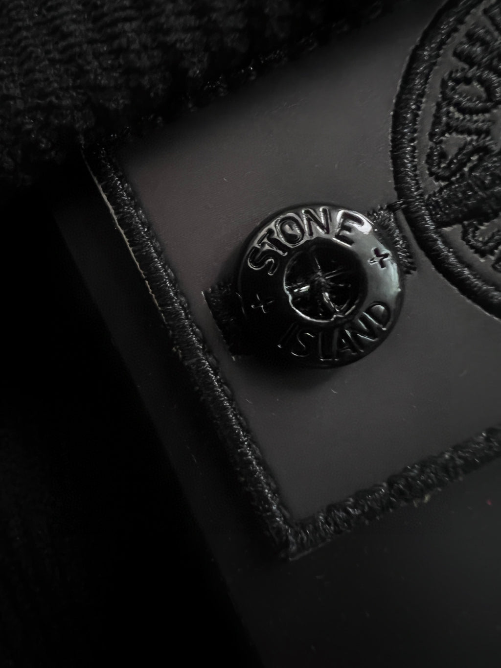 Embossed Stone Island logo on dark fabric patch