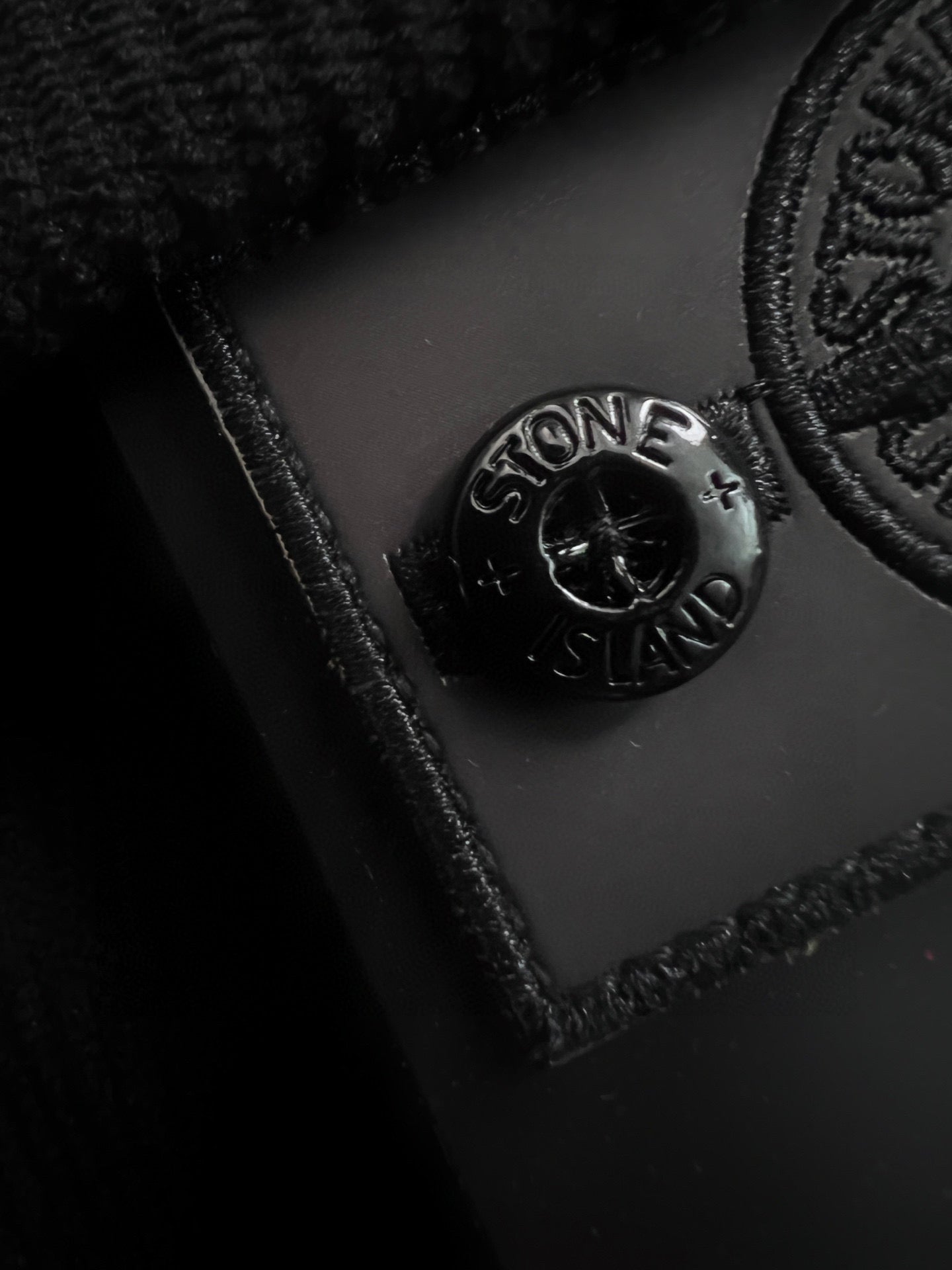 Embossed Stone Island logo on dark fabric patch