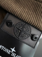 Embossed Stone Island logo leather patch on textured brown fabric