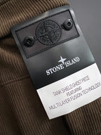Black leather brand patch with embossed Stone Island logo on brown fabric