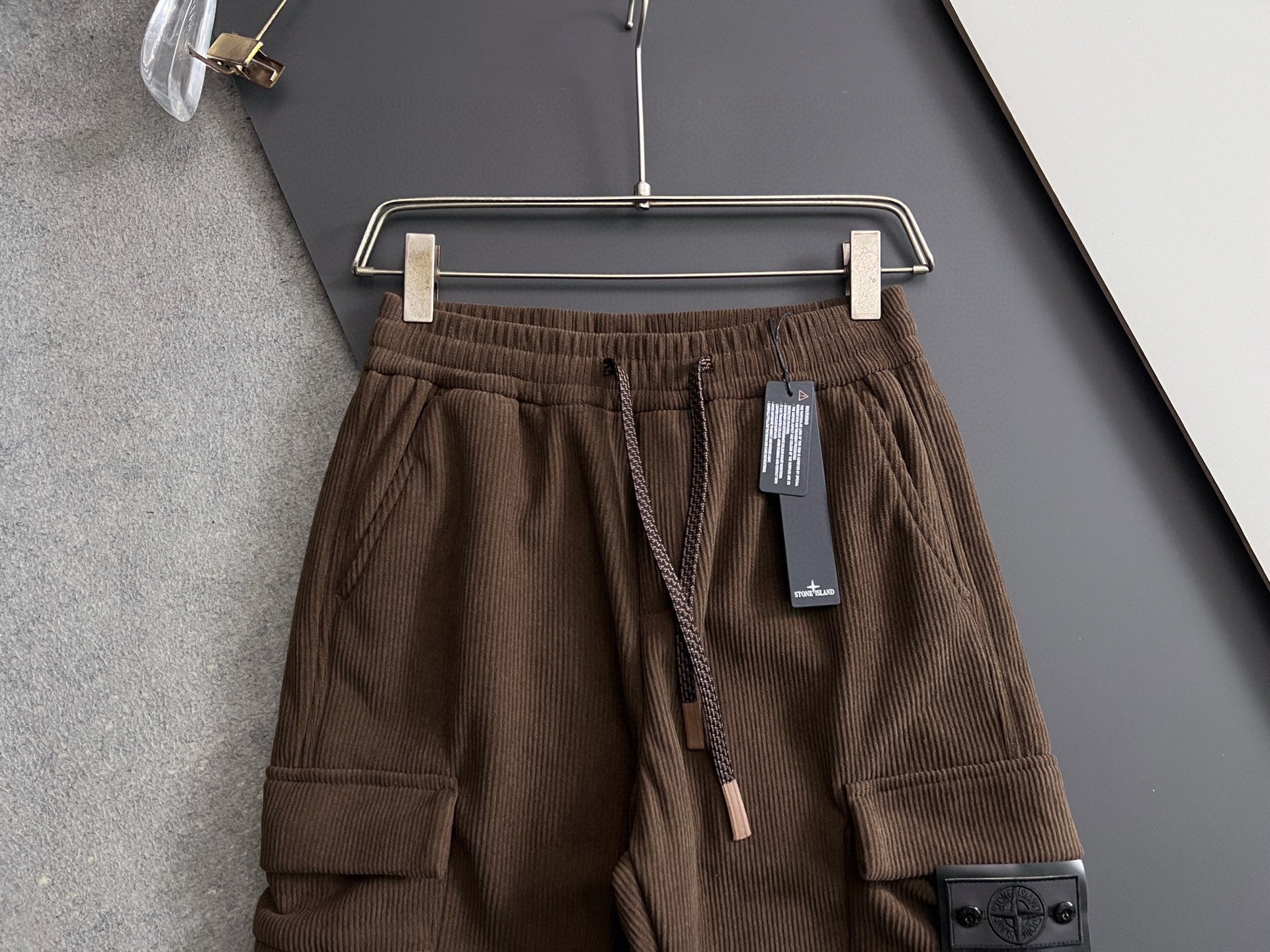 Brown cargo pants on hanger with elastic waistband, drawstring, and pocket detail