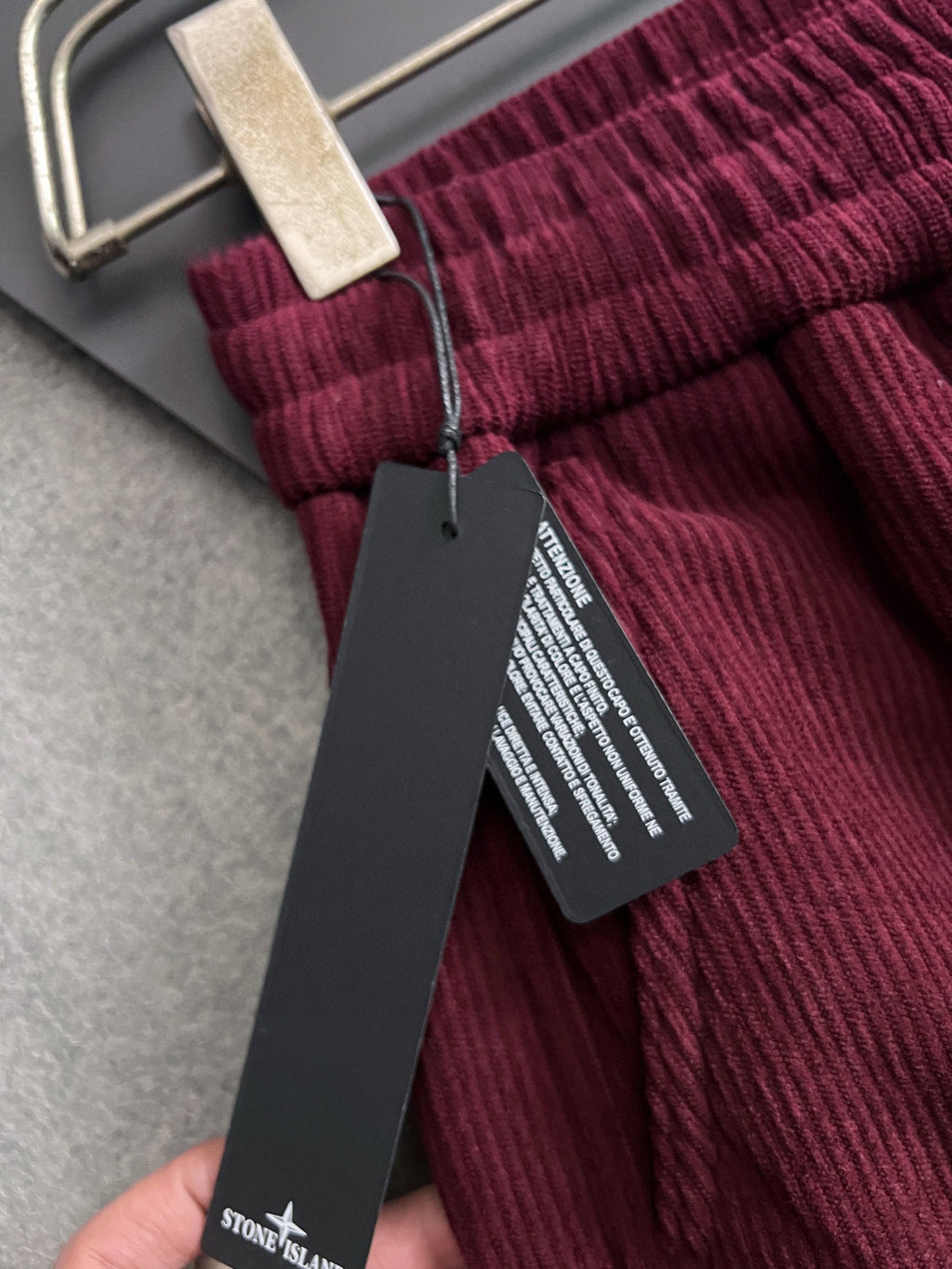 Burgundy pants with ribbed waistband, drawstring, and black hanging tag