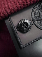 Black Stone Island logo patch with circular emblem on burgundy fabric