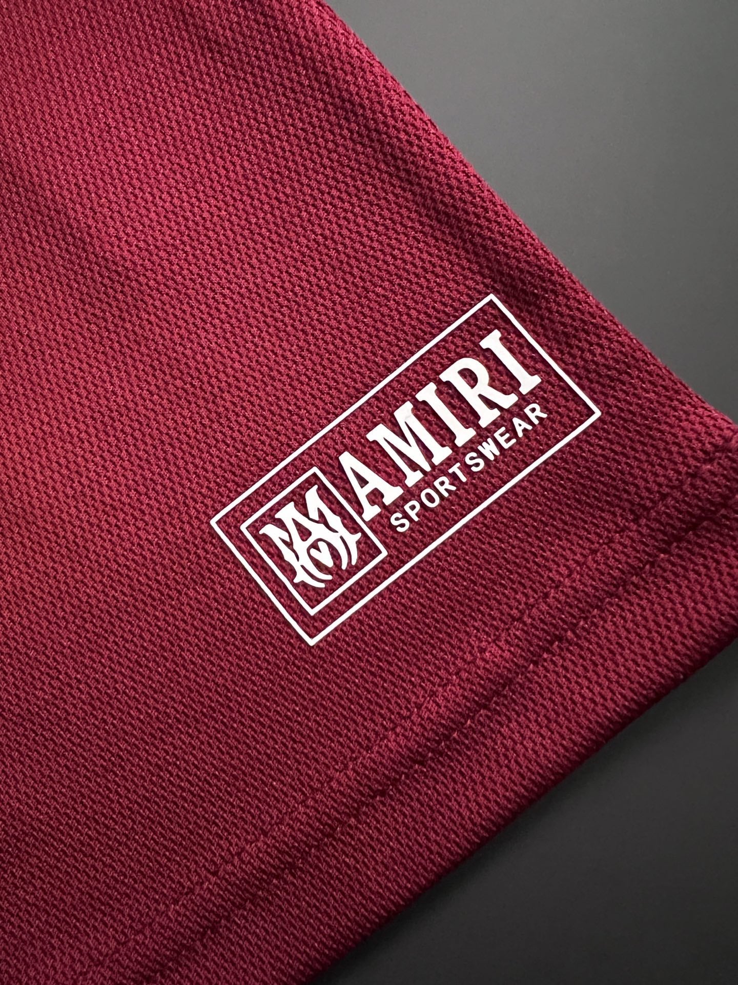 Burgundy fabric tag patch with AMIRI and SPORTSH?EART branding and logo