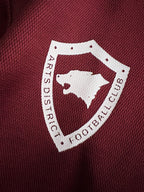 Burgundy fabric with a white crest patch and text across the badge