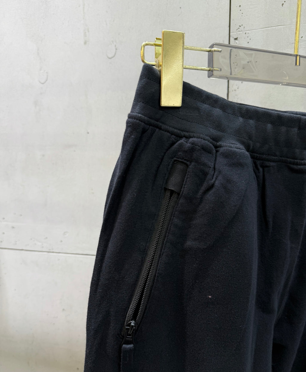 Black cargo pants detail: zip pocket and gathered waistband