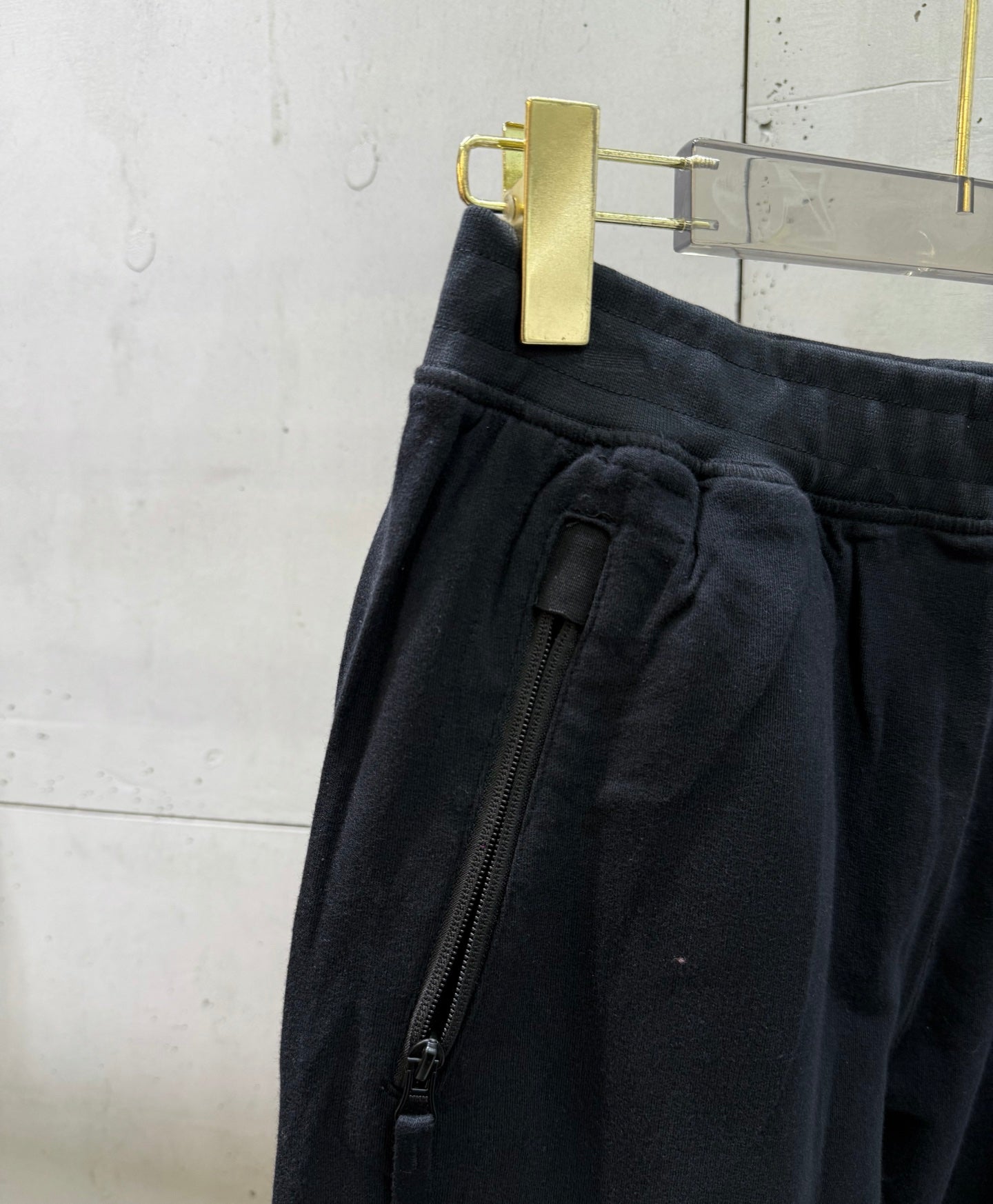Black cargo pants detail: zip pocket and gathered waistband