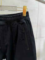 Black cargo pants detail: front zip pocket and stitched waistband