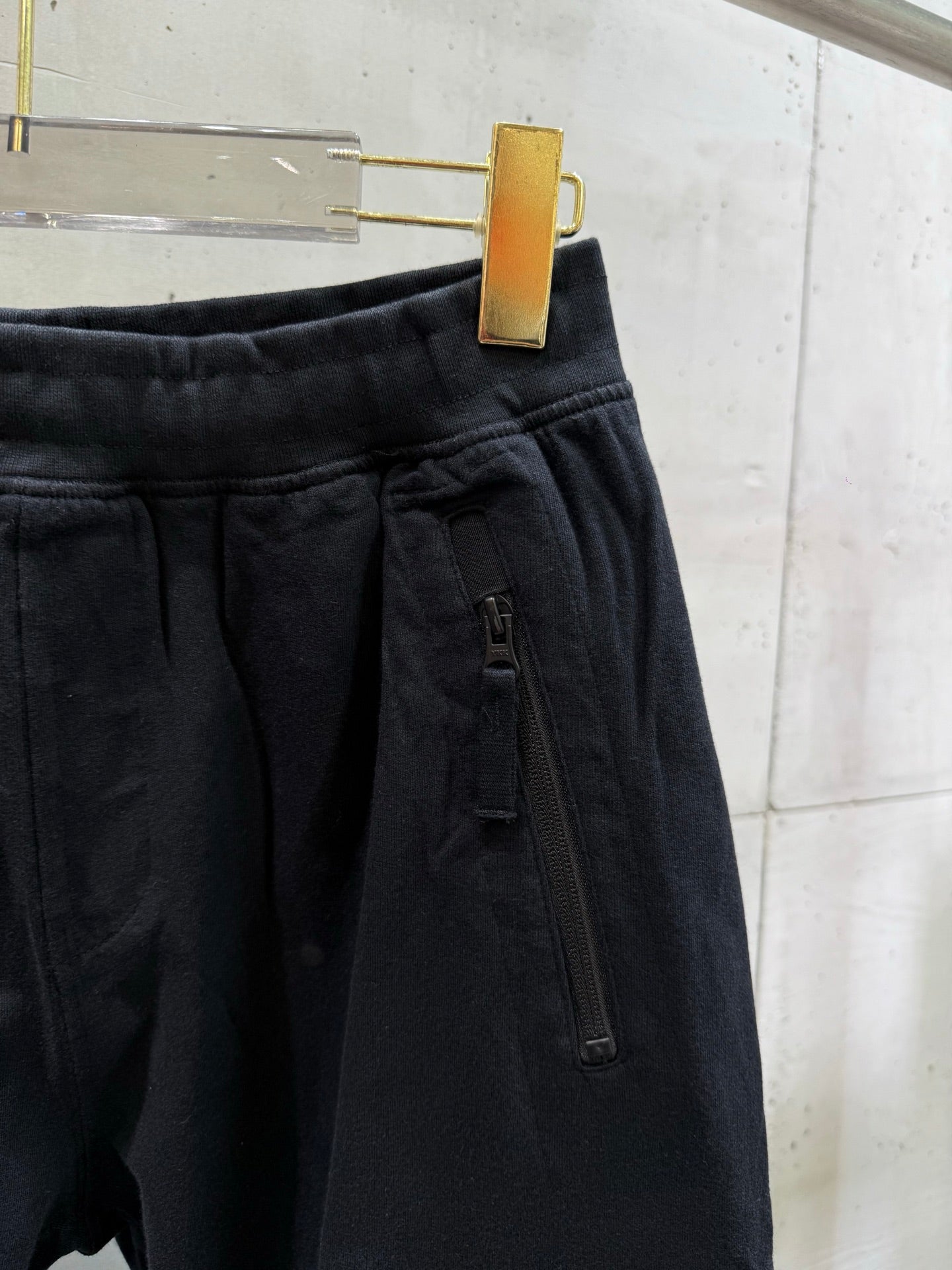 Black cargo pants detail: front zip pocket and stitched waistband