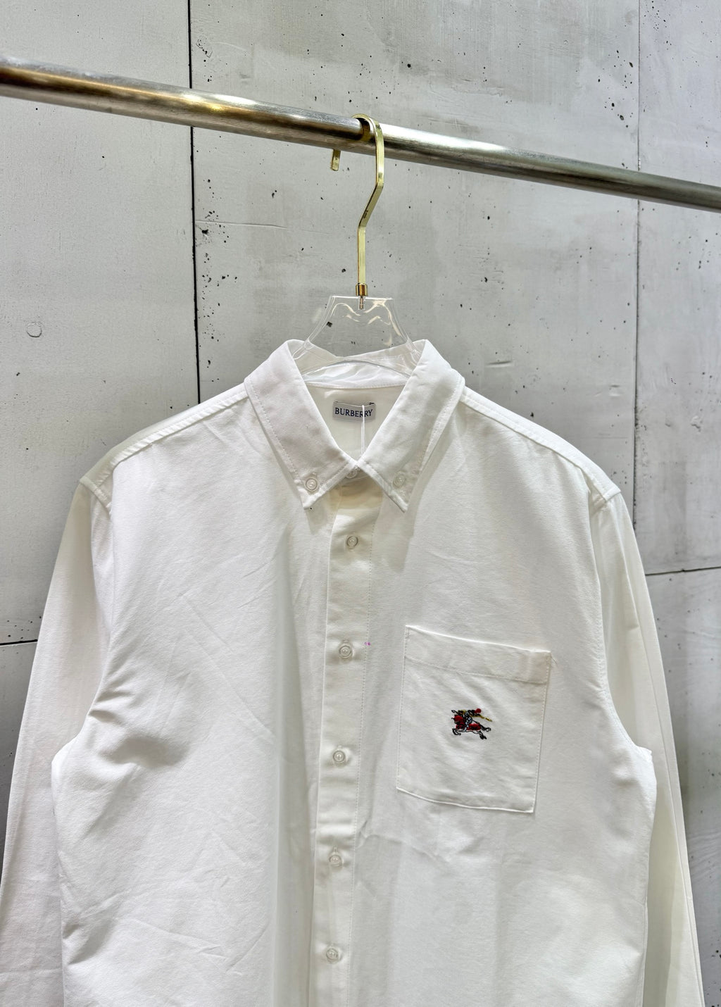 White long-sleeve button-up shirt with chest pocket and embroidered logo