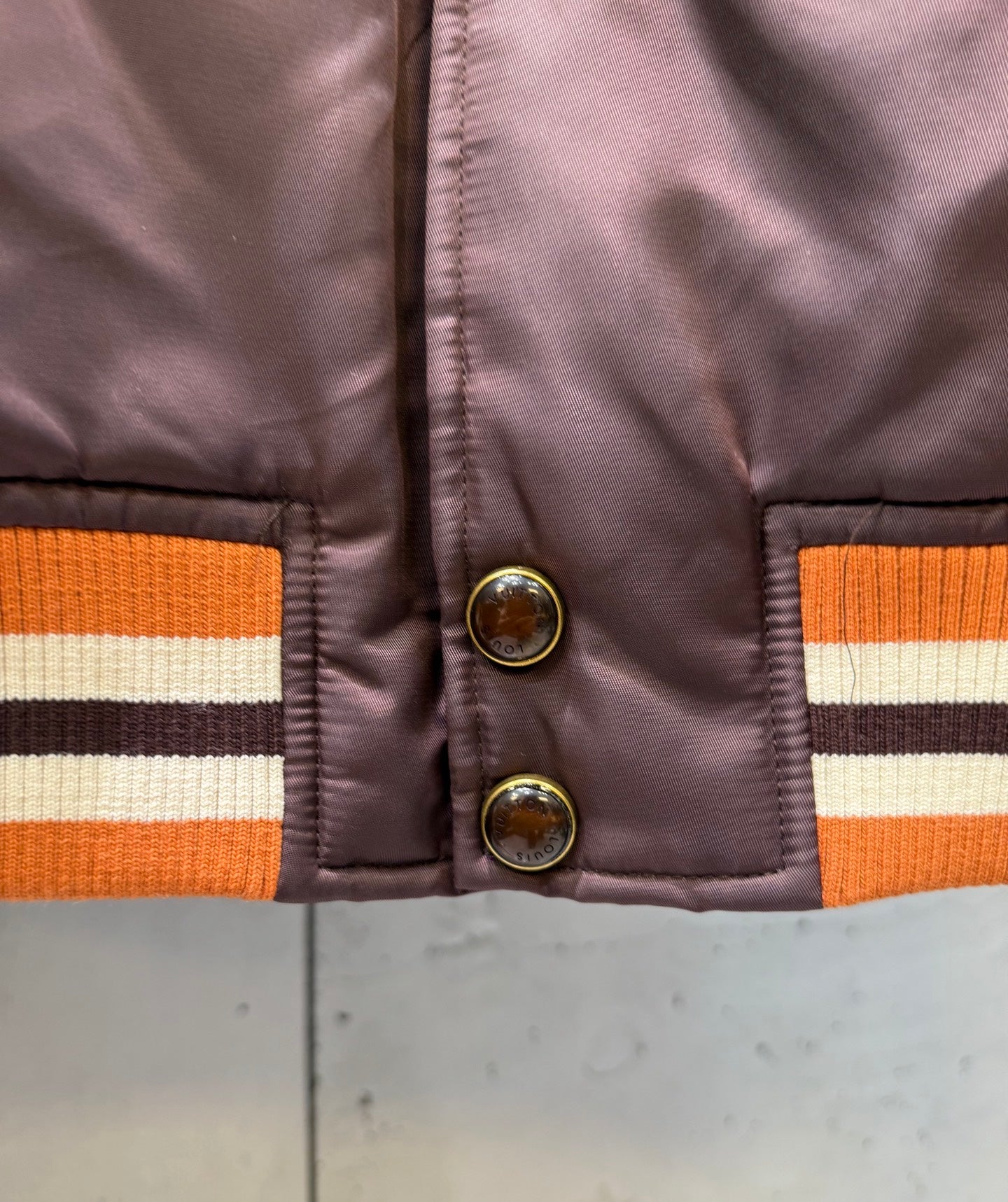 Burgundy bomber jacket with ribbed orange stripe cuffs and two-button closure