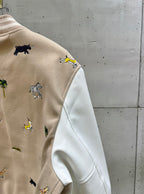 Louis Vuitton jacket arm close-up with animal embroidery on beige and white sleeves.
