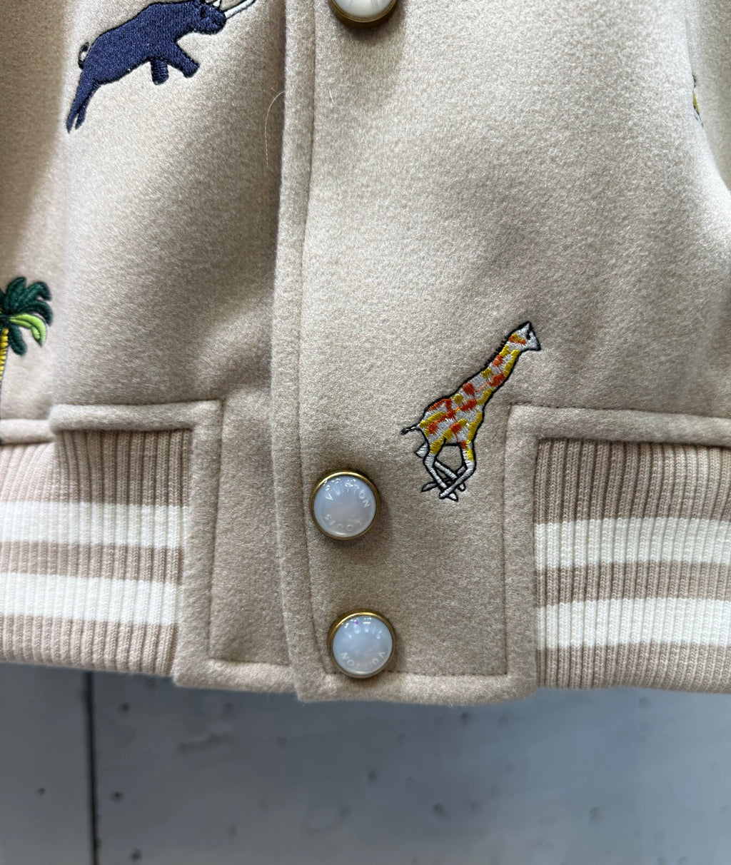 Louis Vuitton jacket front close-up with snap buttons and colorful animal embroidery.