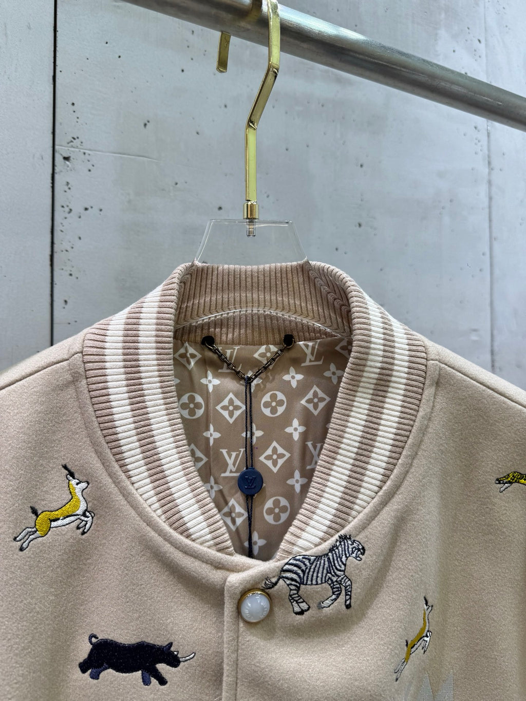 Louis Vuitton varsity jacket close-up: ribbed stand collar with patterned lining and button.