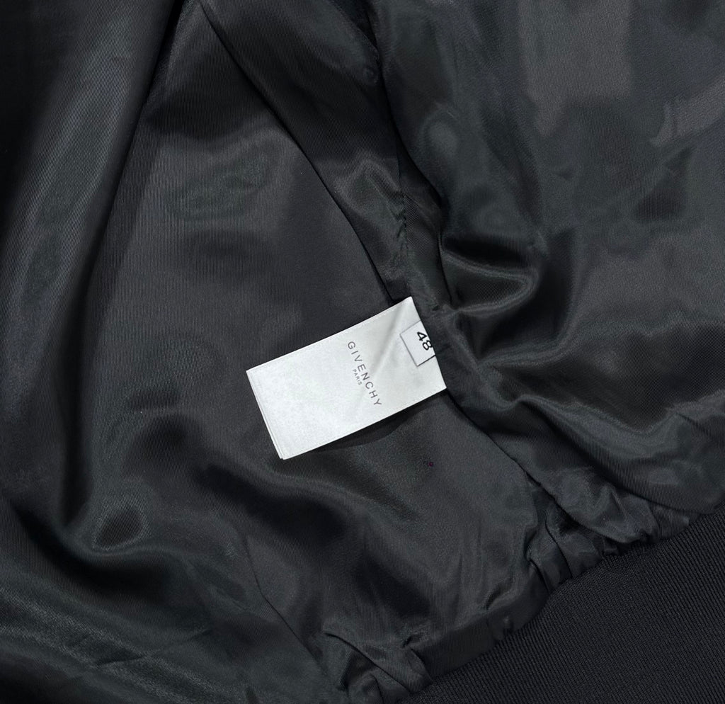 Black bomber jacket fabric close-up with inner label tag