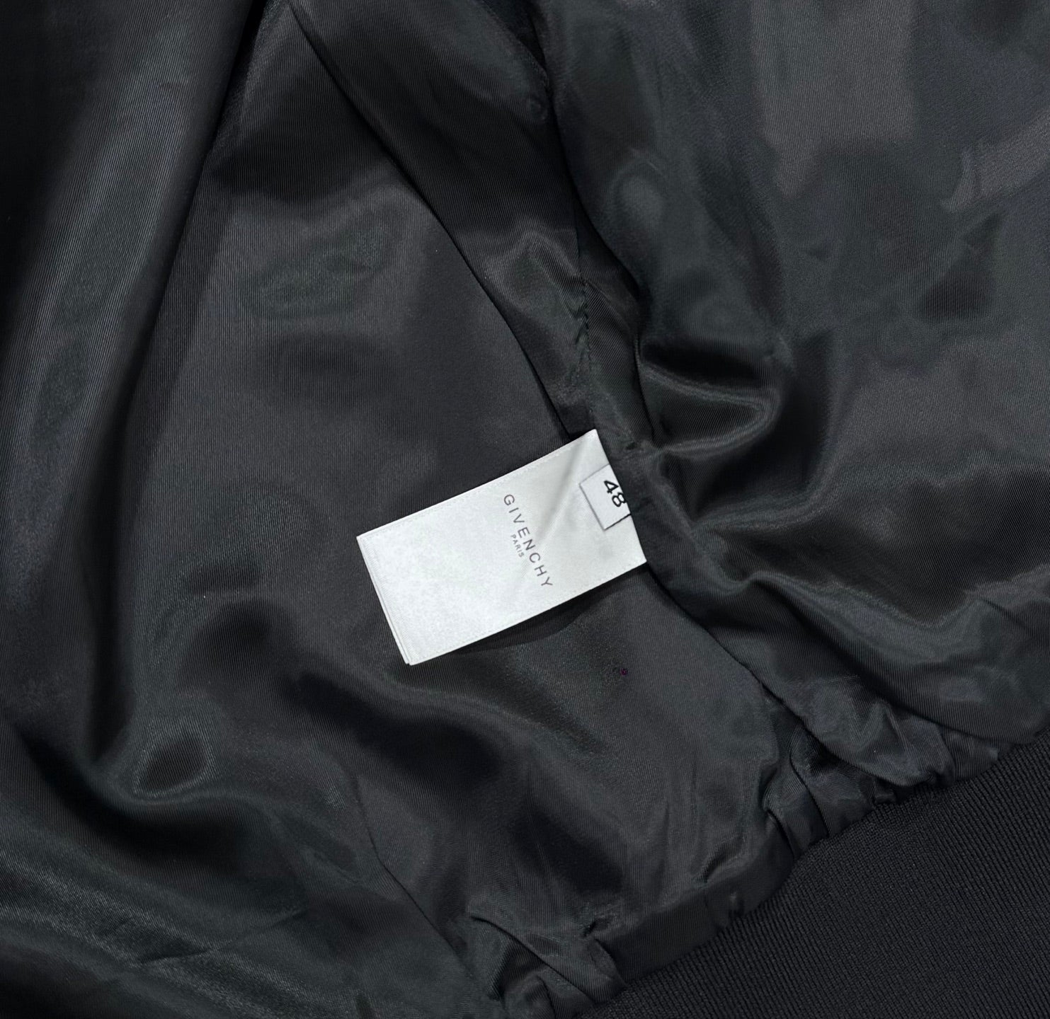 Black bomber jacket fabric close-up with inner label tag