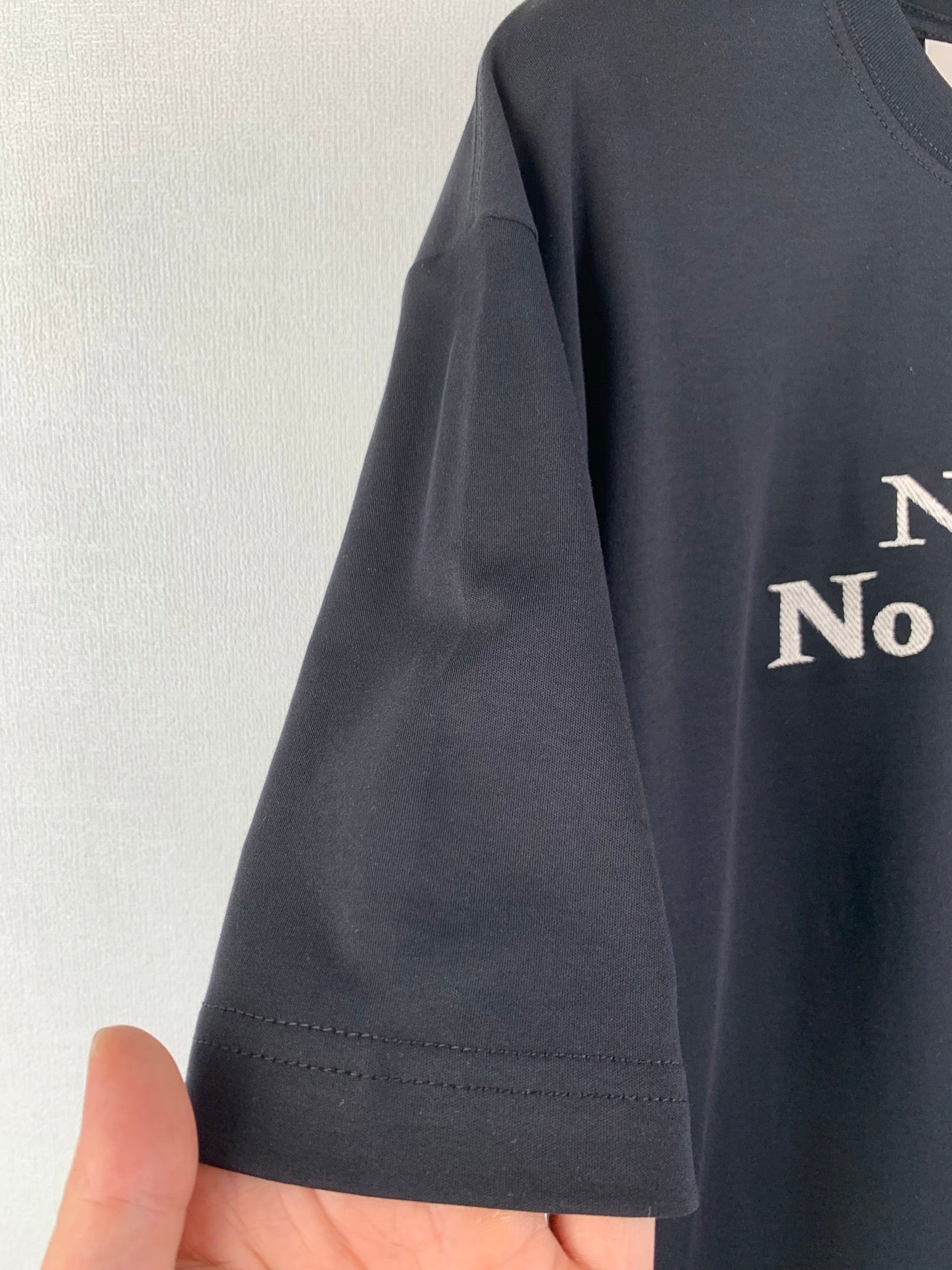 Dark gray T-shirt sleeve hem detail with front graphic partially visible