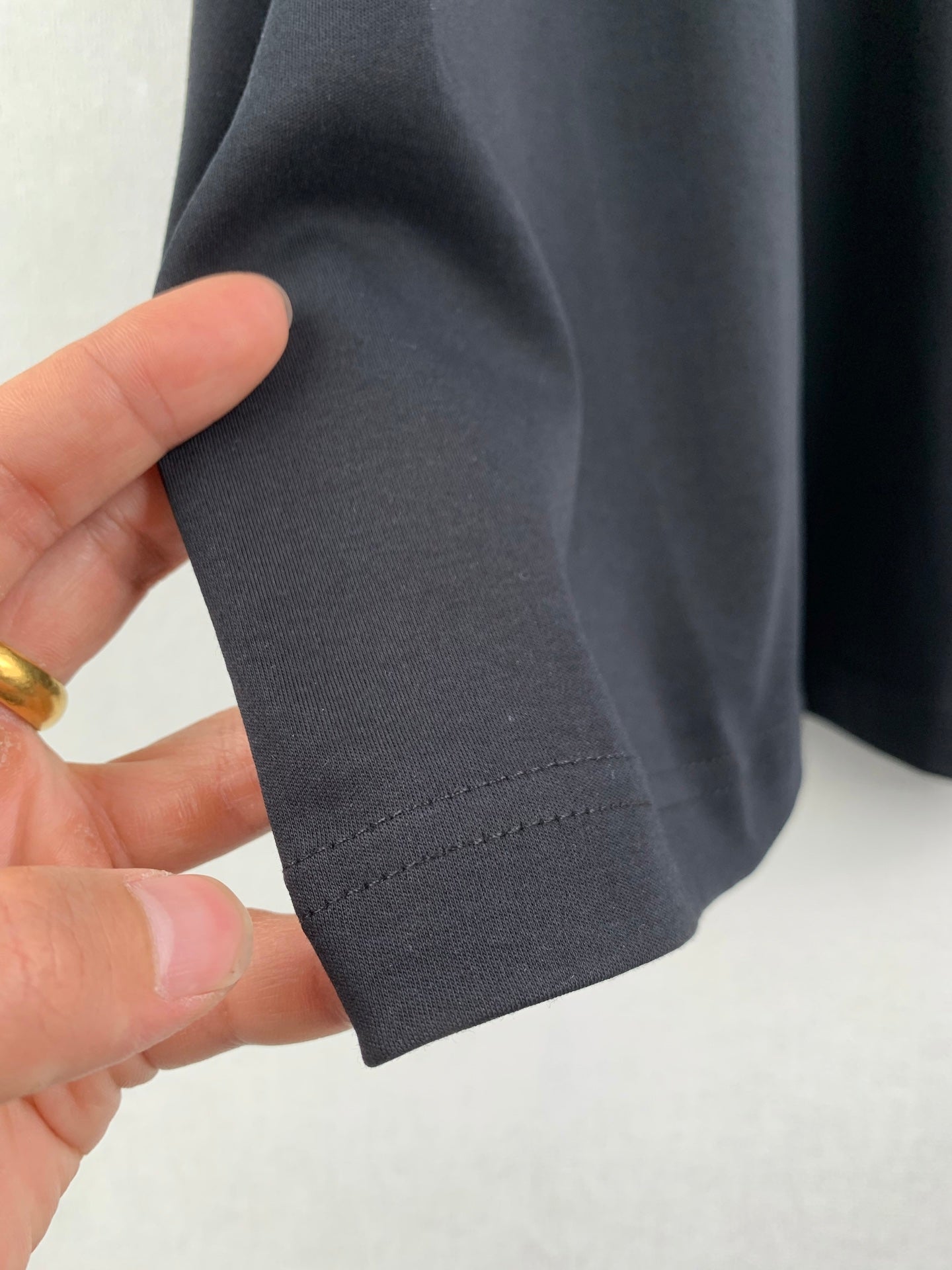 Dark gray T-shirt sleeve cuff and stitching detail, folded