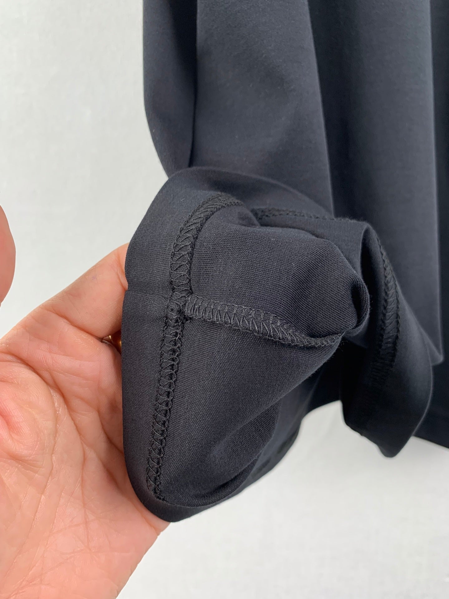Dark gray T-shirt sleeve end with stitched cuff detail, close-up