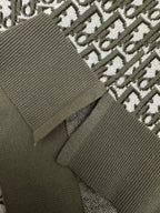 Dark green polo knit close-up with ribbed cuff and logo repeat fabric