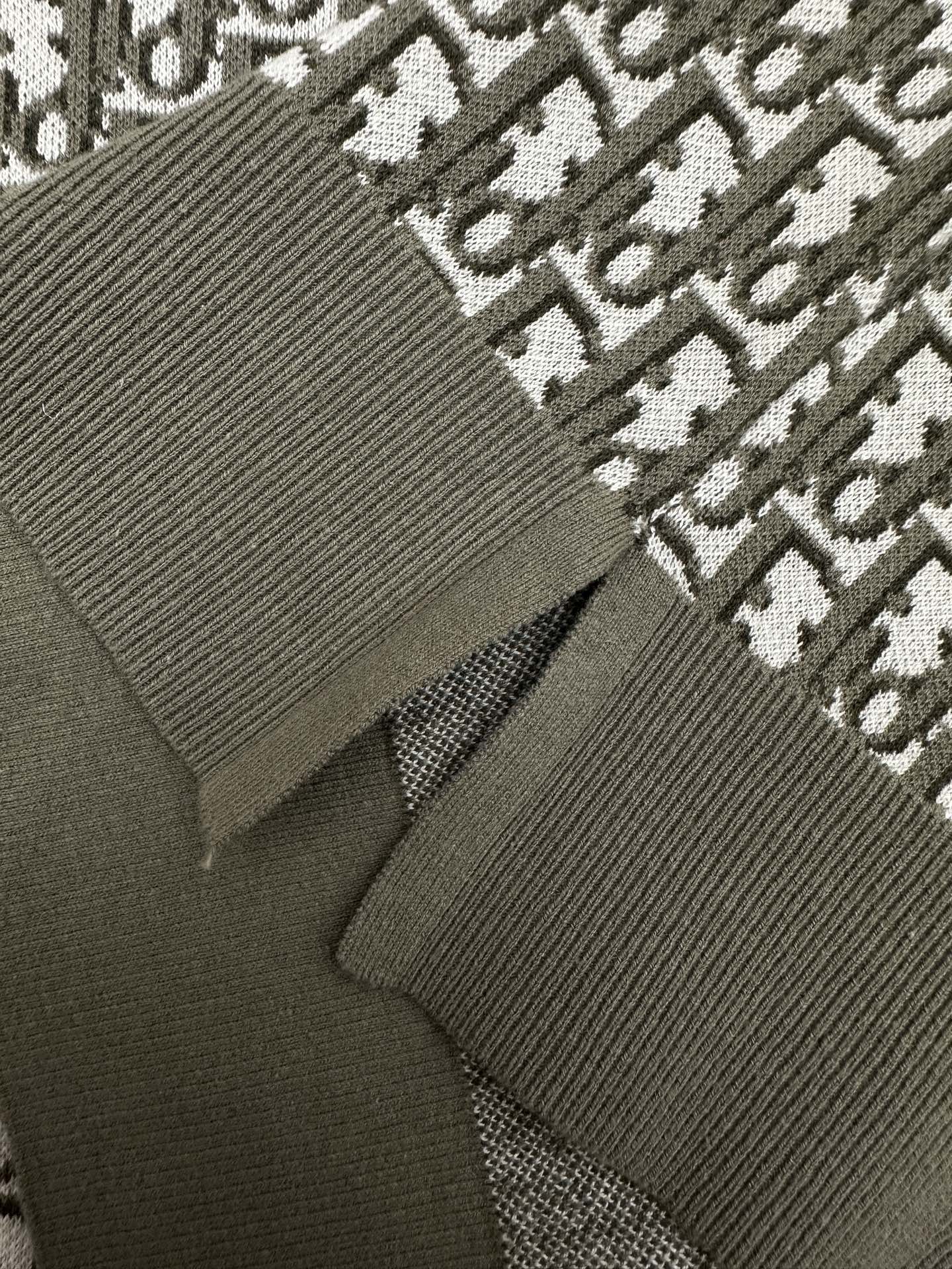 Dark green polo knit close-up with ribbed cuff and logo repeat fabric