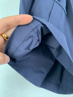 Hand holding navy Prada shorts fabric near pocket seam