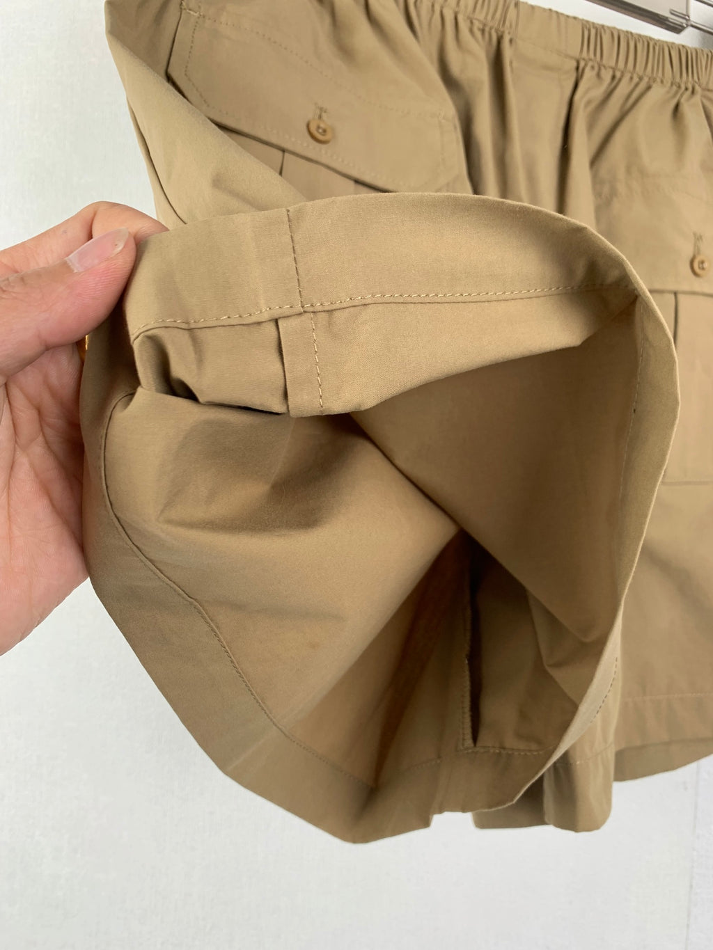 Olive shorts held open, showing front pocket opening and waistband
