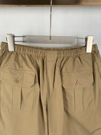 Olive shorts with elastic waistband and front flap patch pockets, close-up