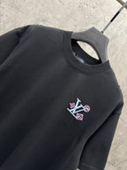 Black T-shirt neckline with small multicolor LV-style logo patch